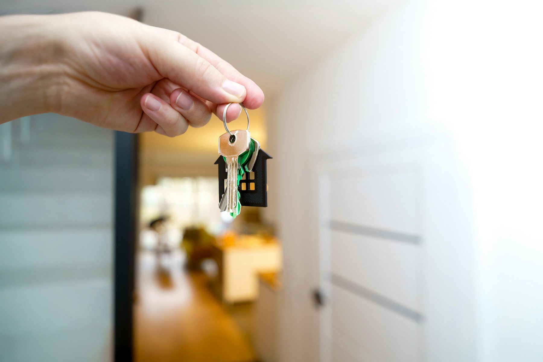 Hand holding apartment keys in the doorway of a new home