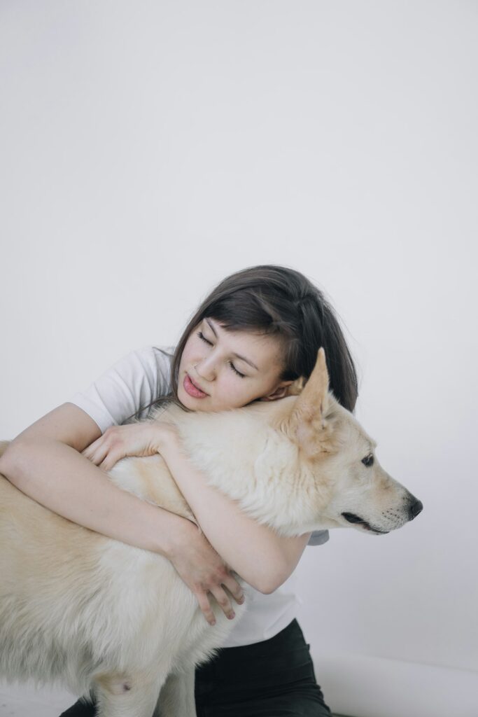 Woman resting her head on her calm white dog