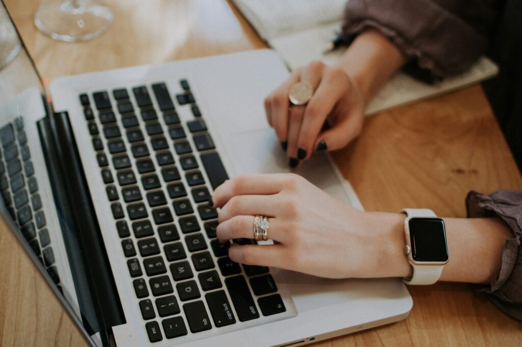 Hands typing on a laptop on a wooden table